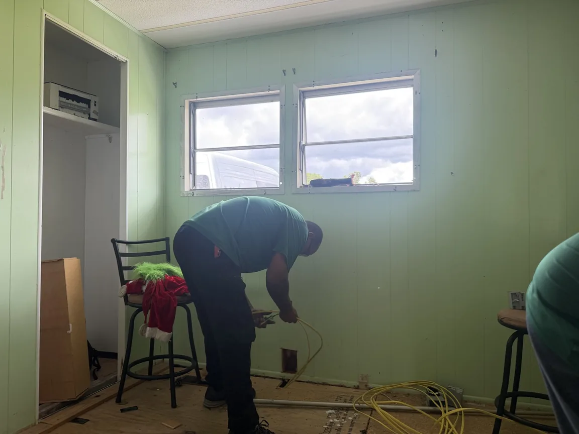 Mister Safety electrician routing new cable beside wall openings during a home rewire in Brooksville, Florida