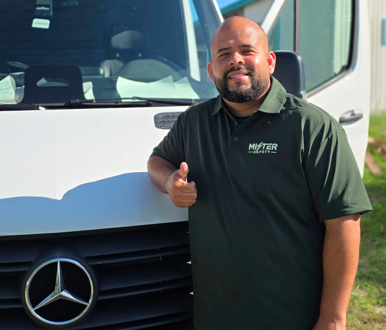 Hector, a Mister Safety electrician, giving a thumbs-up beside a Mercedes-Benz service van